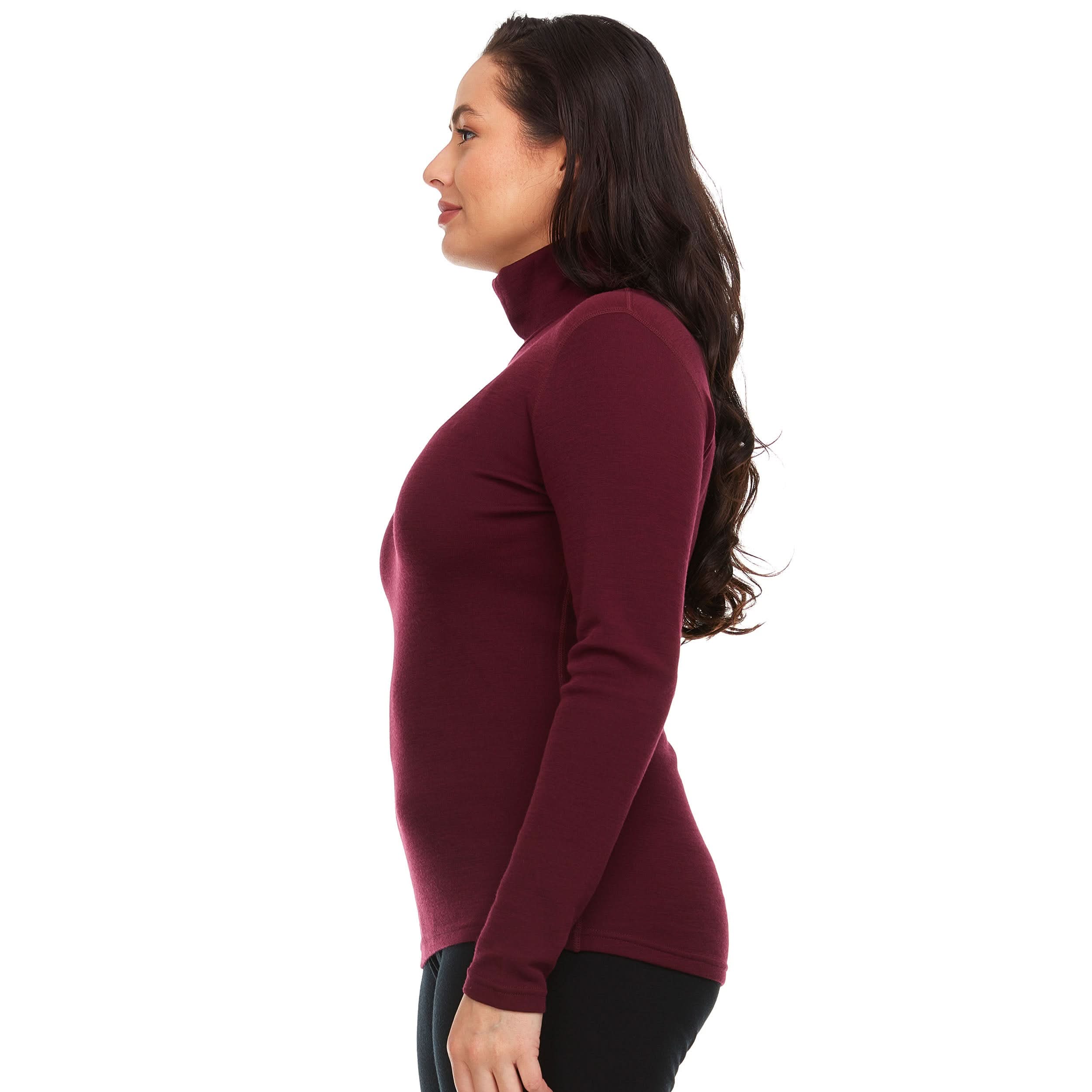 Left-facing side view of a woman wearing a burgundy midweight merino wool turtleneck sweater, showing the raised fitted collar, long close-fitting sleeves, shaped waist, and hip-length hem