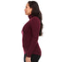 Left-facing side view of a woman wearing a burgundy midweight merino wool turtleneck sweater, showing the raised fitted collar, long close-fitting sleeves, shaped waist, and hip-length hem