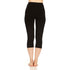 Back full-length view from waist to feet of a woman wearing black Osceola midweight merino wool three-quarter base-layer bottoms, showing the high waistband, centered rear seam, close-fitting legs, and even mid-calf cuffs