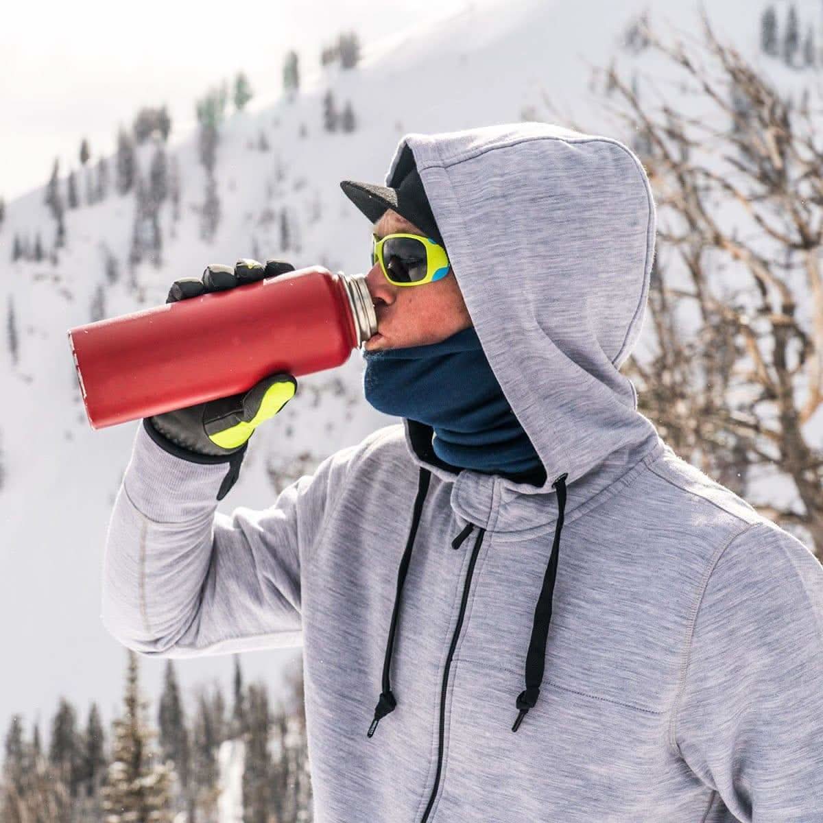 A man stops on his winter hike to take a sip from his thermos. The heavyweight brushed wool Kodiak Fleece Hoodie, crafted with thumbholes and a drawstring to bundle you up for wicked cold days!