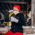 A woman sits on the step of her camp lodge to sip on a warm beverage from a thermos. The woman is wearing a Minus33 hat, neck gaiter, fingerless gloves, and a heavyweight merino wool full zip sweater. The sweater features a full length zipper, a two and a half inch collar, two zippered pockets, and thumbholes.