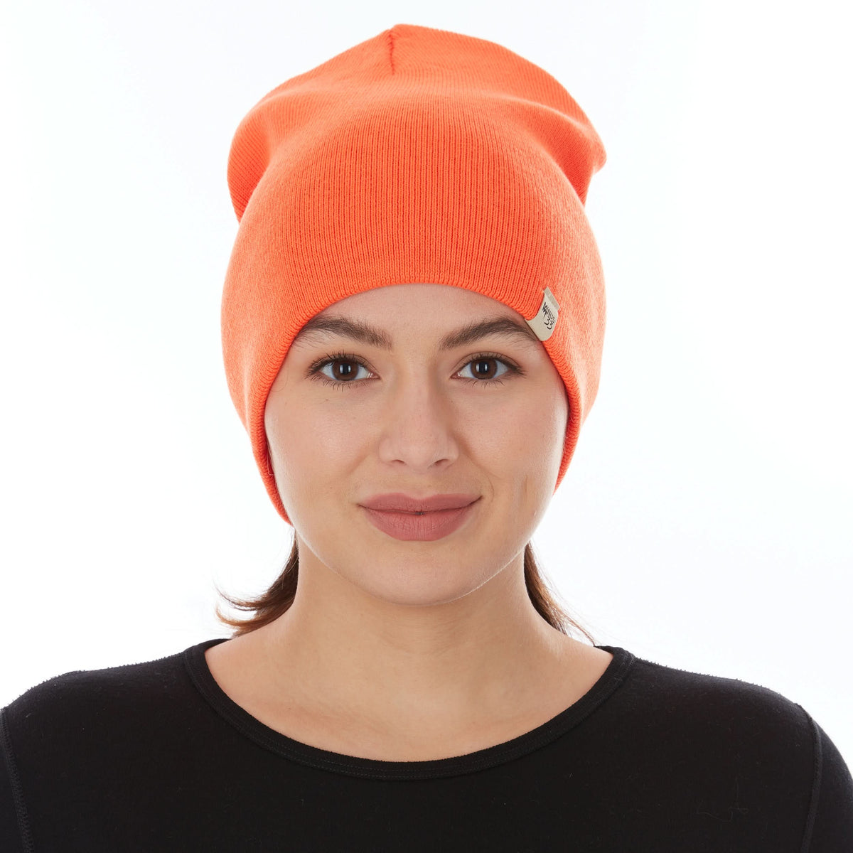 Front view of a female model wearing a blaze orange heavyweight 100% merino wool beanie with a folded cuff