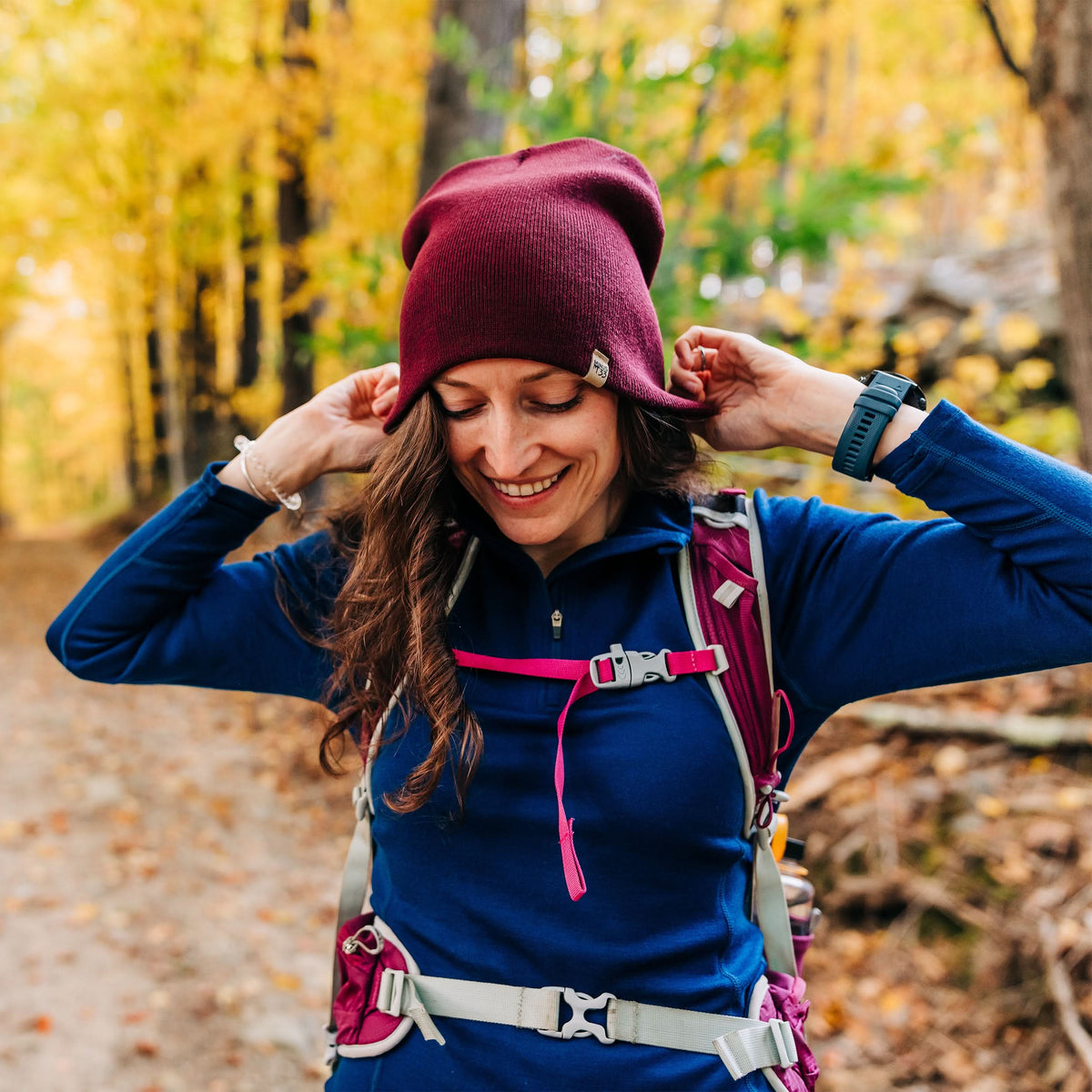 A woman on the trail models a heavyweight, super soft, one hundred percent merino wool beanie. This heavyweight beanie is the warmest hat that we offer, perfect for hiking through the White Mountains, or sitting at a bonfire in January.
