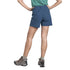 A model from the back wearing a pair of high-waisted, slate blue hiking shorts, paired with hiking boots and a green shirt, against a solid white background.