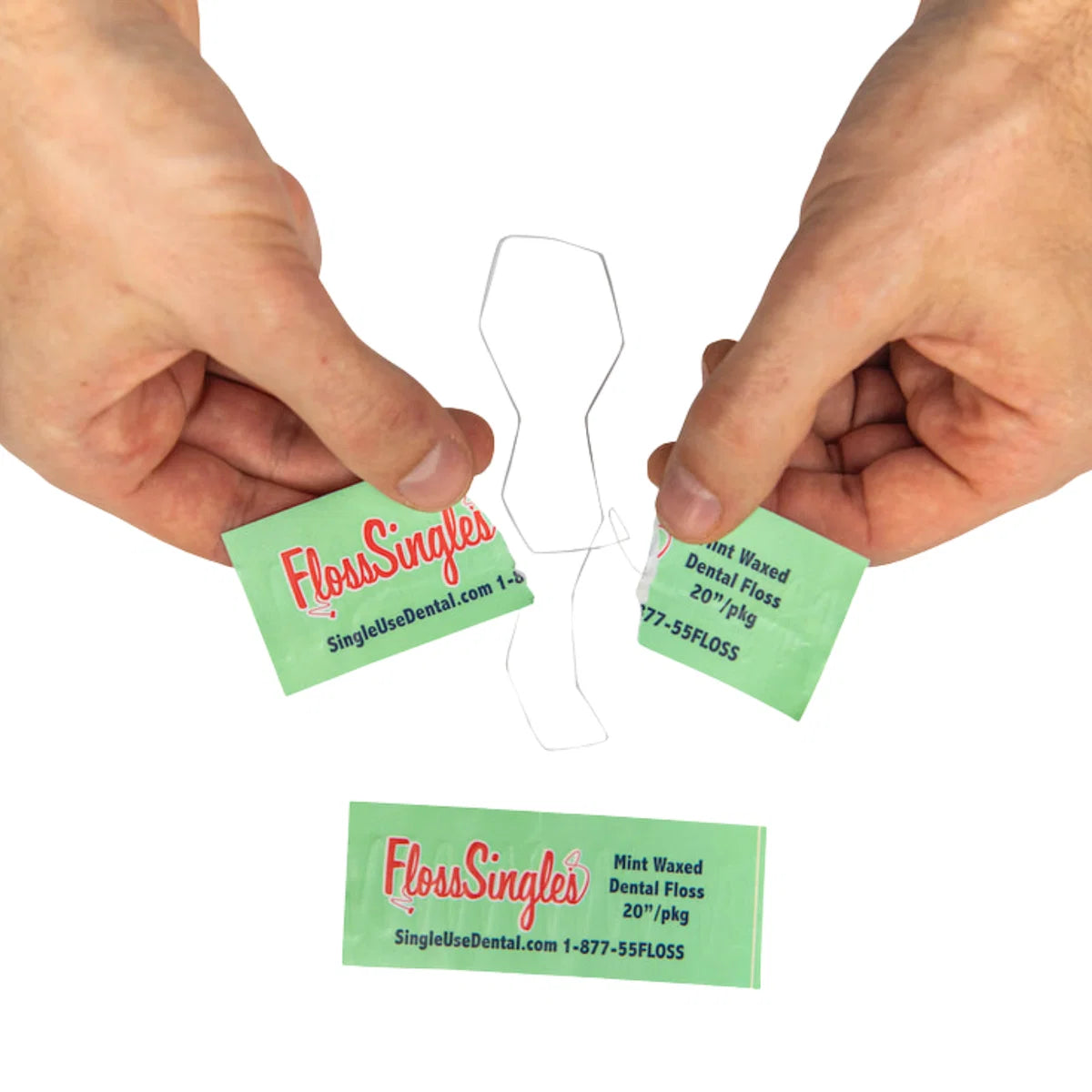 Hands holding a floss signals package torn open with a singal use dental floss hanging out. An unopened green package is on the ground. 
