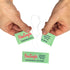 Hands holding a floss signals package torn open with a singal use dental floss hanging out. An unopened green package is on the ground. 
