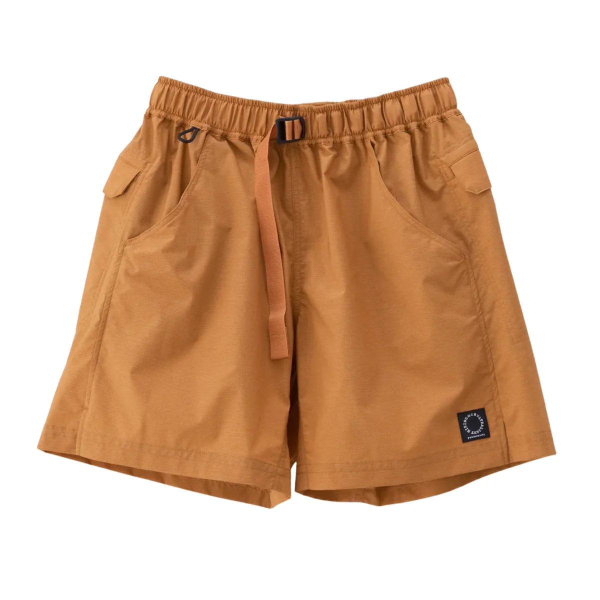 A pair of shorts in a warm camel brown color, featuring an elastic waistband with a drawstring, side pockets, and a small circular logo patch on the lower left leg, displayed against a solid white background.