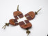 Four brown split-finger archery tabs shown together with stitched leather panels and adjustable cords.