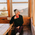 Midweight - Men's Long Sleeve Button Up 100% Merino Wool. Our best-selling Midweight fabric now as a long-sleeve henley. midlayer, man seated alone with a red mug beside a cabin window