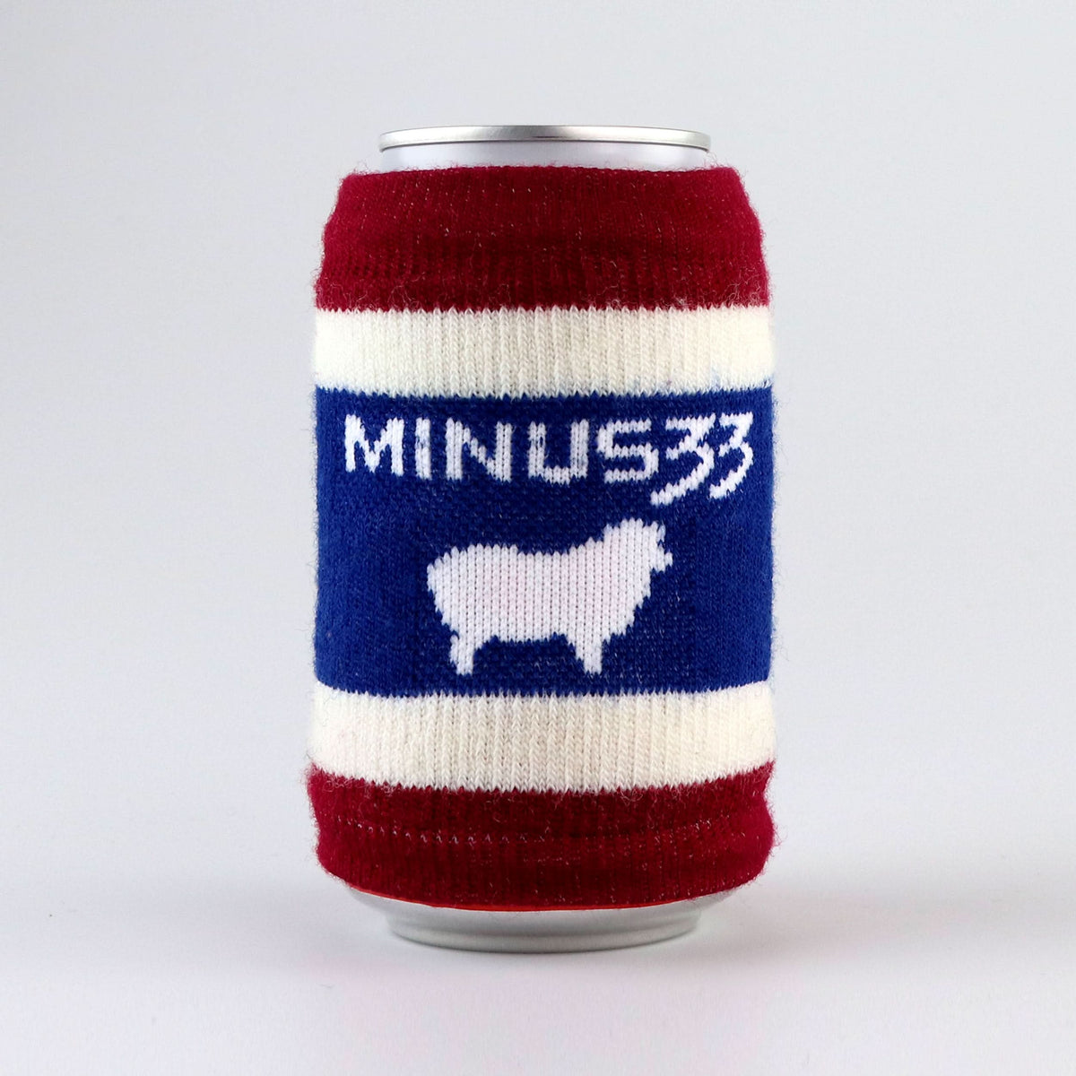 Red, white, and blue knit can cooler featuring a Minus33 wordmark and white sheep graphic.