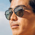 Sunski Astra Polarized Sunglasses - Black Forest - Close-up of a person wearing sunglasses with a clear sky background